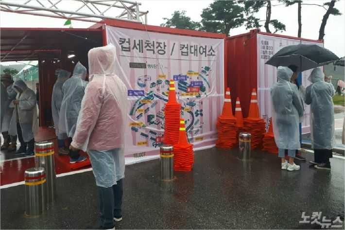 컵 세척장과 대여소 위치를 안내해 주는 현수막 앞에 주차 칼라콘들이 쌓여 있다. (사진=유선희 기자)
