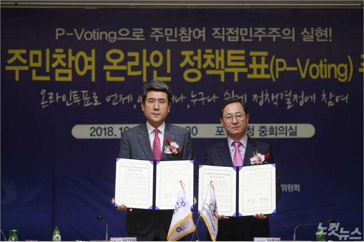 이강덕(왼쪽) 포항시장과 경북선관위 김종대 사무처장이 주민참여 온라인 정책투표 업무협약서를 들고 있다(사진=포항시 제공)