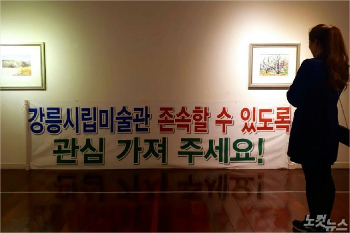 한 시민이 '강릉시립미술관 존속 요구' 현수막을 바라보고 있다. (사진=유선희 기자)