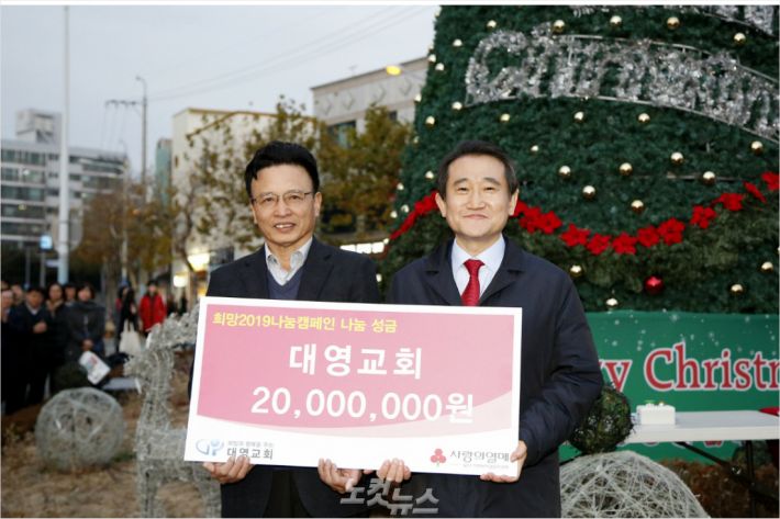 울산 북구 대영교회는 25일 교회 앞 중앙광장에서 열린 크리스마스 트리 점등식에서 북구청에 이웃돕기 성금 2000만원을 전달했다. 사진 왼쪽부터 이동권 북구청장, 조운 담임목사.(사진 = 울산 북구 제공)