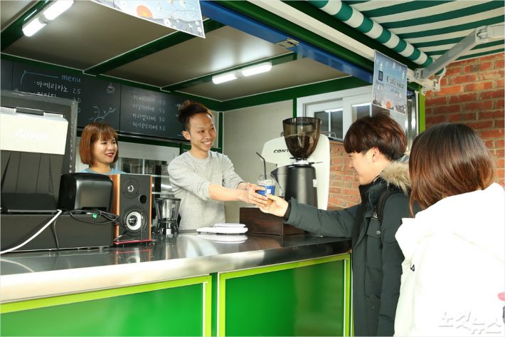 한남대 베트남 유학생들이 창업한 카페에서 손님에게 커피를 건네고 있다. (사진=한남대 제공)