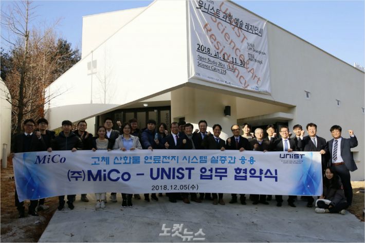 UNIST(울산과학기술원)와 민간기업 (주)미코가 5일 대학 학술정보관에서 고체 산화물 연료전지(SOFC)를 실용화하기 위한 공동 연구 업무협약을 체결했다. 체결식에 참석한 사람들이 과일집 앞에서 단체 사진을 찍고 있다.(사진 = UNIST 제공)