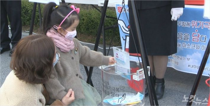 한국구세군의 코로나19 극복 캠페인 '내 마음을 담다'에 한 소녀가 마스크를 기부하고 있다.