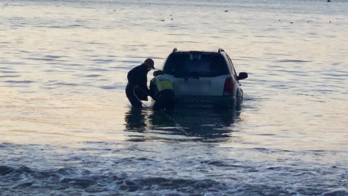 A vehicle built on a white sandy beach in Pohang, swept away by waves