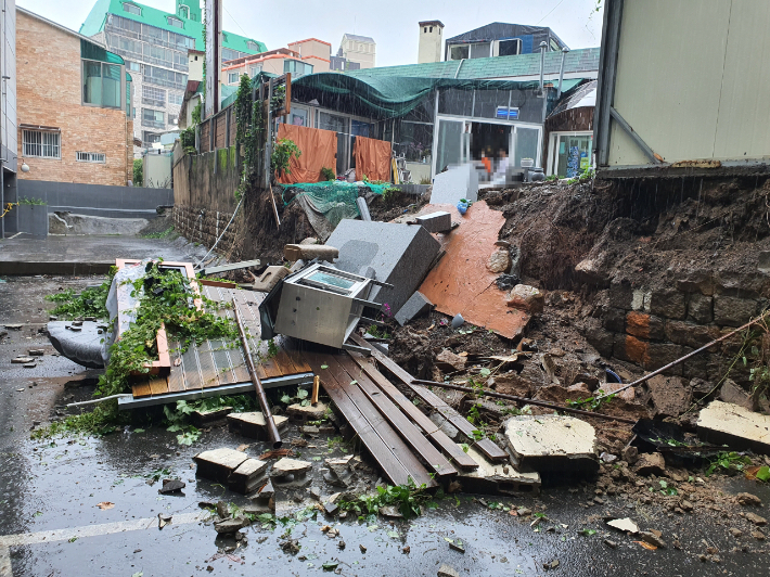 6일 부산지역에 100㎜가 넘는 폭우가 내려 피해가 속출했다. 이날 오전 부산 동래구 한 사찰에서 담벼락이 무너져 차량 한 대가 파손됐다. 부산경찰청 제공
