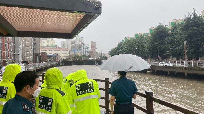 7일 부산 사하구 한 하천에서 경찰과 소방이 물에 휩쓸린 A(70대)씨를 수색하는 모습.  부산경찰청 제공
