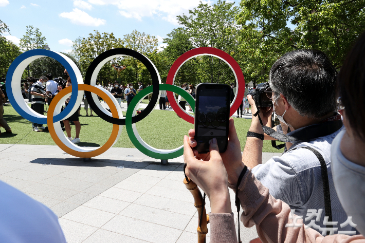 일본 항공자위대 블루임펄스는 21일 오후 도쿄 올림픽스타디움 상공에서 오륜기를 그리는 행사를 진행했다. 이날 경기장 인근에 행사를 구경하러 나온 사진을 찍고 있다. 도쿄=올림픽사진공동취재단