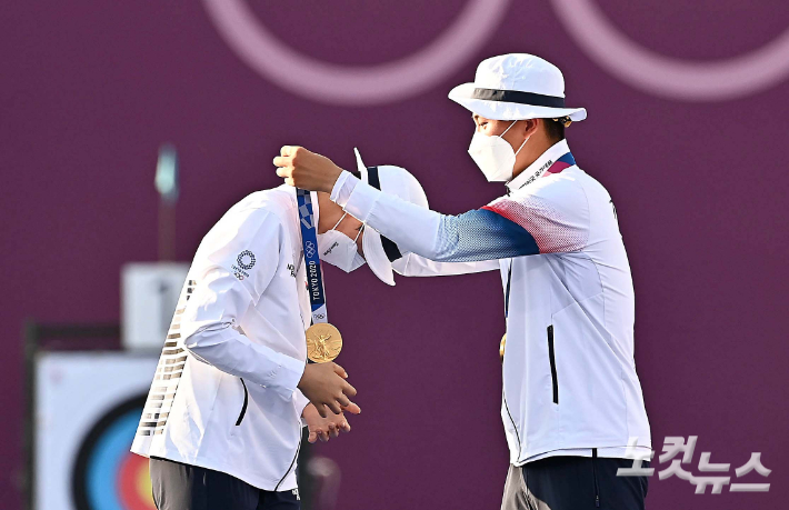 '2020 도쿄올림픽' 양궁 혼성 단체전에서 금메달을 획득한 김제덕이 24일 오후 일본 도쿄 유메노시마 공원 양궁장에서 안산에게 직접 금메달을 목에 걸어주고 있다. 올림픽사진공동취재단