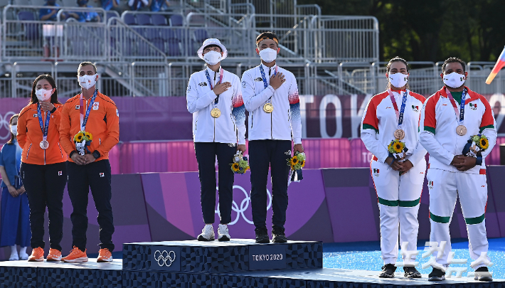 '2020 도쿄올림픽' 양궁 혼성 단체전에서 금메달을 획득한 김제덕, 안산이 24일 오후 일본 도쿄 유메노시마 공원 양궁장에서 애국가를 부르고 있다. 올림픽사진공동취재단