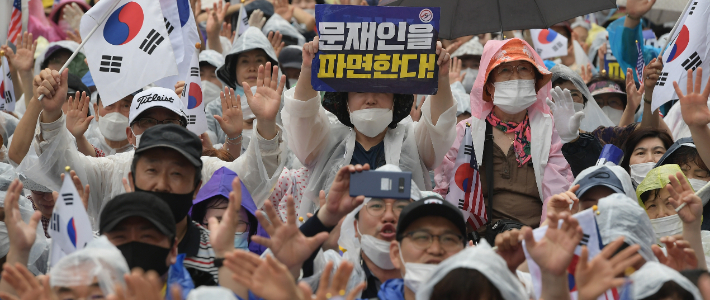 1년전인 2020년 8월 15일 서울 종로구 동화면세점 앞에서 열린 보수단체의 광복절 집회에서 참석자들이 태극기와 문재인 대통령 파면을 촉구하는 피켓을 들고 있다. 이한형 기자