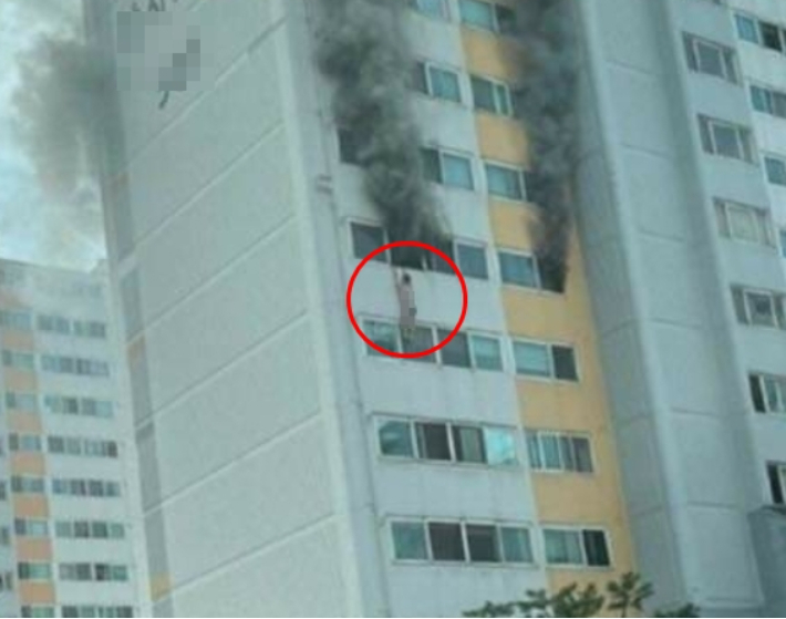 불이 난 아파트 창문에 매달려 있는 주민. 독자 제공