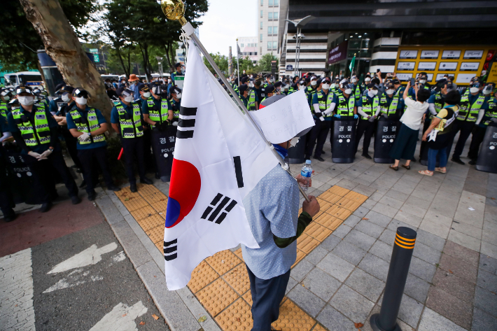 지난 15일 국민혁명당의 기자회견이 열린 서울 종로구 주얼리시티 인근에서 태극기를 든 시민이 접근을 통제하는 경찰 앞에 서 있는 모습. 연합뉴스