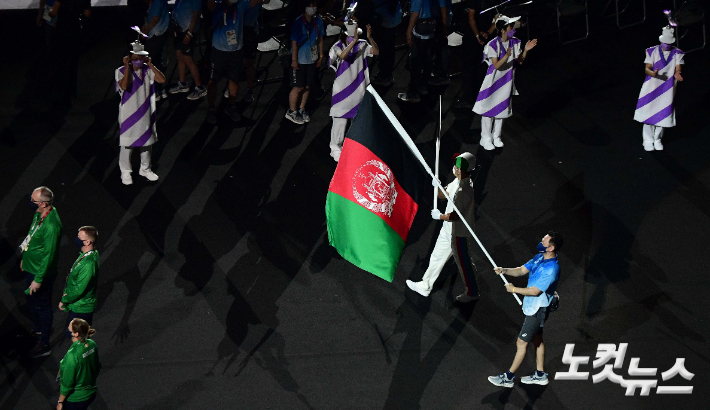 지난 24일 오후 일본 도쿄 국립경기장에서 열린 2020 도쿄패럴림픽 개회식에서 아프간 국기가 자원봉사자의 손에 들려 입장하고 있다. 이슬람 무장단체 탈레반이 정권을 재장악한 아프간은 선수단을 파견하지 못할 것으로 알려졌지만 개회식 선수단 행진에 아프간 국기가 합류하며 연대의 메시지를 전 세계에 전했다. 도쿄(일본)=사진공동취재단