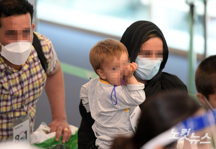  과거 한국을 도왔던 아프가니스탄 협력자와 그 가족들이 26일 오후 우리 공군 수송기에 탑승해 인천공항에 도착, 코로나19 유전자 증폭(PCR) 검사를 받기 위해 보안구역으로 이동하고 있다.  사진공동취재단