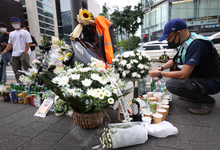 지난 27일 오후 서울 강남구 선릉역 인근 도로에 전날 사망한 오토바이 배달원을 추모하는 국화꽃 등이 놓여져 있다. 오토바이 배달원은 전날 오전 신호를 기다리다 화물차에 치여 숨졌다. 민주노총 서비스연맹 서비스일반노조 이날 추모 행사를 열고 이 사고를 산업재해로 인정해줄 것을 촉구했다. 연합뉴스