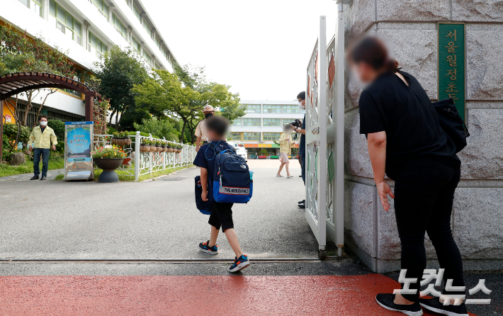 서울 강서구 월정초등학교 정문에서 한 학부모가 등교하는 아들의 뒷모습을 바라보고 있다. 사진공동취재단