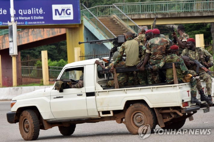 5일(현지시간) 서아프기카 기니의 무장 군인들이 수도 코나크리의 거리에서 중무장한 채 이동하고 있다. [AFP=연합뉴스] 연합뉴스