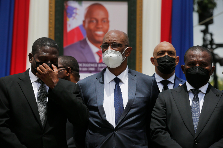 살해된 모이즈 대통령 사진 앞에 선 앙리 아이티 총리(가운데). 연합뉴스