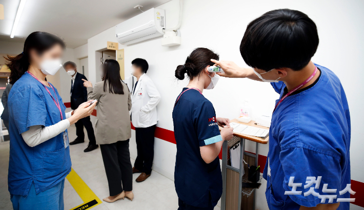 12일 오후 서울 중구 국립중앙의료원 중앙예방접종센터에서 치료병원 종사자들이 백신 접종을 받기 전 체온을 재고 있다. 황진환 기자