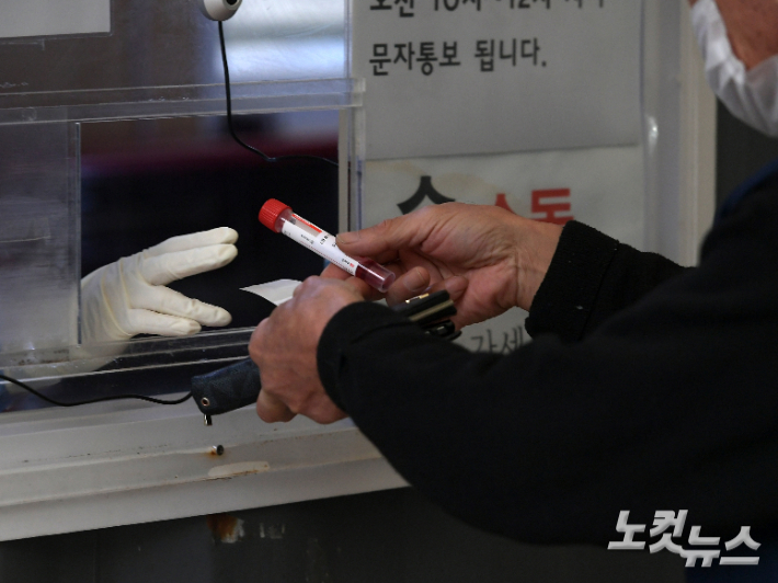 서울 중구 서울역광장에 마련된 임시선별진료소에서 시민들이 검사를 받고 키트를 건네고 있다. 이한형 기자