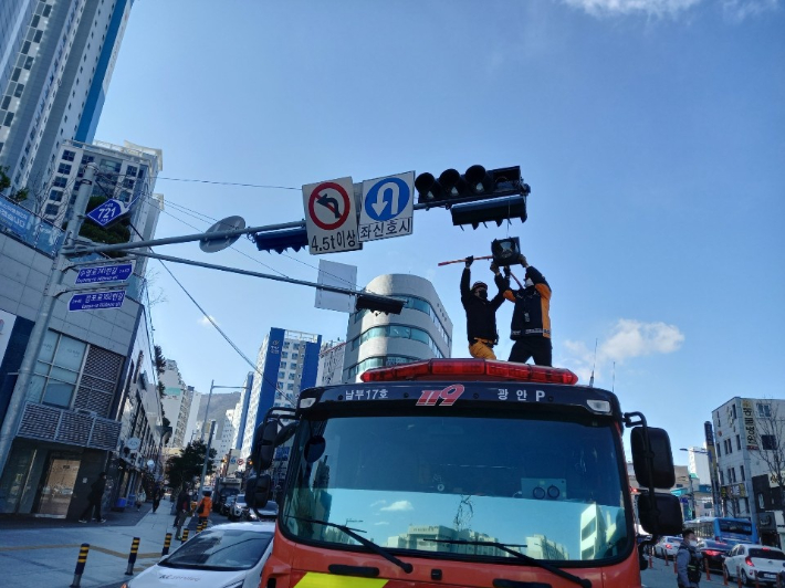 17일 낮 부산 수영구에서 소방대원이 강풍에 흔들린 신호등을 고정하고 있다. 부산소방재난본부 제공