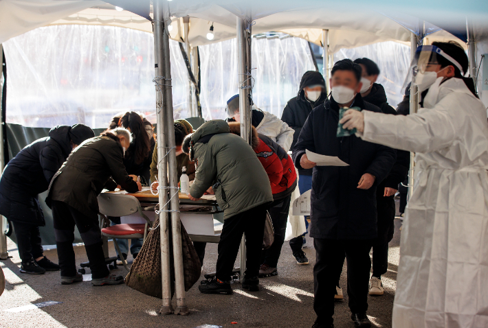 18일 오전 서울역 광장에 마련된 임시 선별검사소에서 시민들이 접수를 위해 수기로 관련 설문지를 작성하고 있다. 연합뉴스