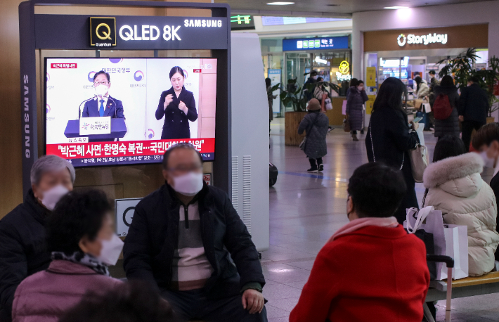 24일 오전 서울역에서 시민들이 박범계 법무부 장관의 사면 관련 발표 방송을 보고 있다. 연합뉴스