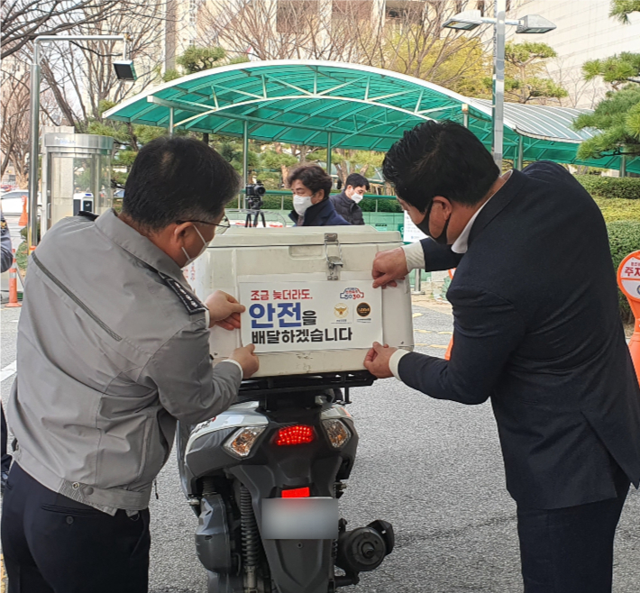 경찰 관계자들이 배달라이더의 배달 박스에 안전운전 스티커를 부착하고 있다. 부산경찰청 제공