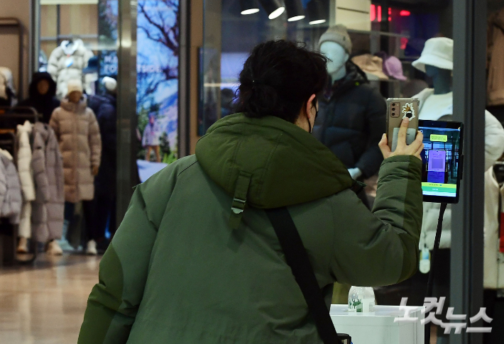 9일 서울 시내 한 백화점 입구에서 시민들이 전자출입명부 QR코드를 찍고 있다. 황진환 기자