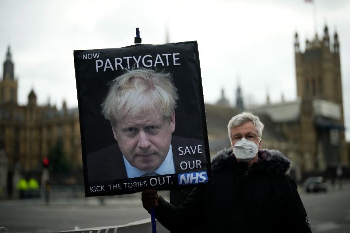 8일(현지시간) 영국 런던 의회 앞 광장에서 시위대가 팻말을 들고 봉쇄령 속 총리실 송년 파티에 항의하는 시위를 벌이고 있다. 연합뉴스