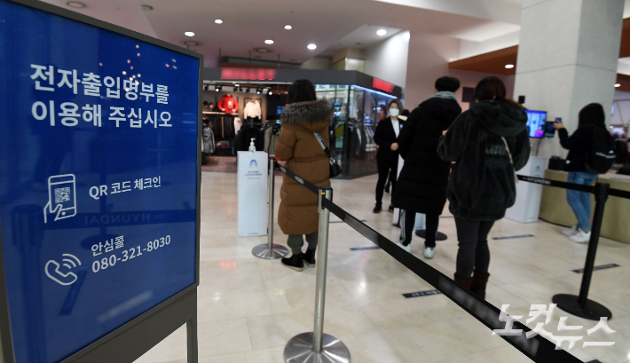 지난 9일 서울 시내 한 백화점 입구에서 시민들이 전자출입명부 QR코드를 찍고 있다. 황진환 기자