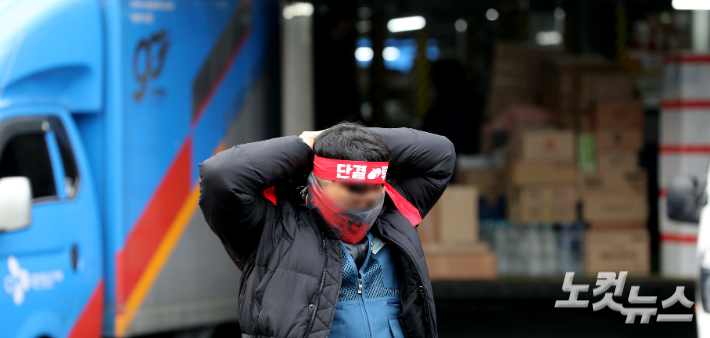 지난해 12월 경기 광주시 중대동 CJ대한통운 성남터미널에서 '택배 노동자 과로사 방지를 위한 사회적 합의 이행을 촉구하는 무기한 총파업 출정식이 열린 가운데 한 택배노동자가 머리끈을 묶고 있다. 황진환 기자