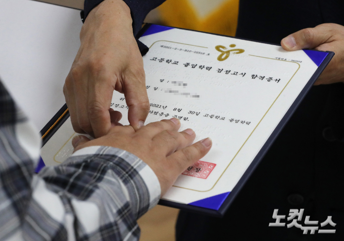 조희연 서울시교육감이 28일 서울 노원구 노원시각장애인복지관에서 열린 '2021년 제2회 찾아가는 검정고시 합격증서 수여식'에서 시각장애인 합격자에게 점자로 된 합격증을 읽어주고 있다. 이한형 기자