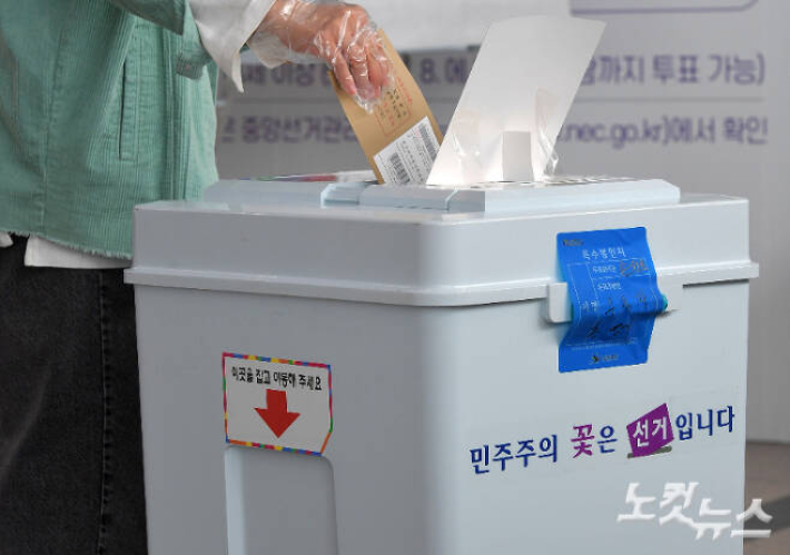 지난해 4·7 재보궐선거 사전투표를 위해 한 시민이 서울 중구 서울역에 설치된 사전투표소에서 비닐장갑을 끼고 투표 하고 있다. 박종민 기자