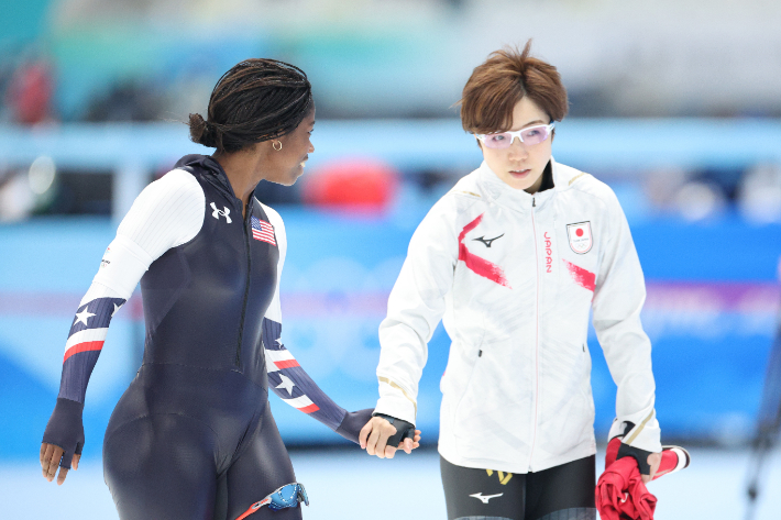 13일 오후 중국 베이징 국립 스피드스케이팅 경기장(오벌)에서 열린 2022 베이징 동계올림픽 스피드스케이팅 여자 500m 경기에 출전한 에린 잭슨(미국)이 결승선을 통과한 뒤 고다이라 나오(일본)와 손을 잡고 있다. 에린 잭슨은 이날 37초 04로 우승했으며 올림픽 스피드스케이트 사상 최초로 메달을 따낸 흑인 여자 선수가 됐다. 연합뉴스