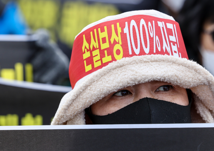 15일 오후 서울 광화문 열린마당에서 열린 ''코로나 피해 실질 보상 촉구 및 정부 규탄대회''에서 자영업자가 손실보상을 촉구하는 내용의 머리띠를 하고 있다. 연합뉴스