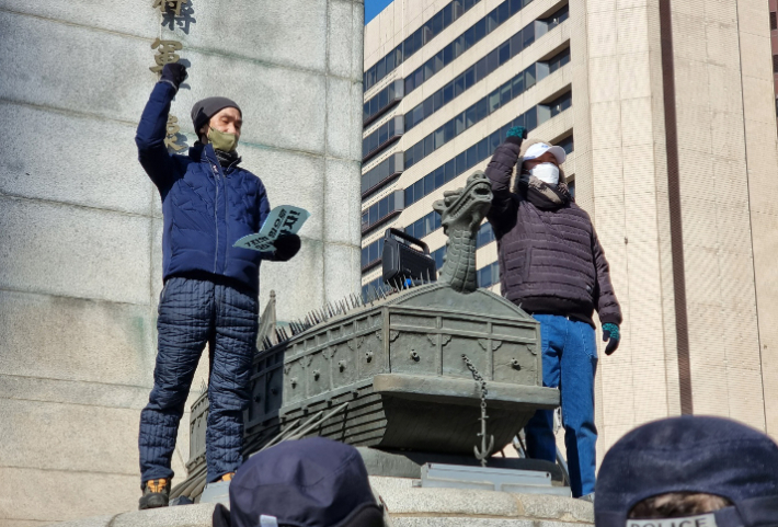 CJ대한통운 택배노동자들이 22일 서울 광화문 광장 이순신동상에 올라가 CJ대한통운과 대화를 촉구하며 구호를 외치고 있다. 연합뉴스