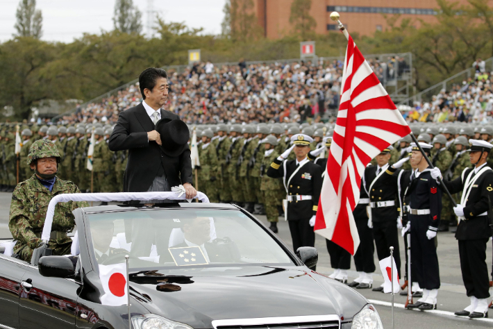 2018년 10월 14일 아베 신조 당시 일본 총리가 일본 수도권 소재 육상자위대 아사카(朝霞) 훈련장에서 자위대원의 경례를 받고 있다. 근처에서 자위대원이 욱일기를 들고 있다. 연합뉴스