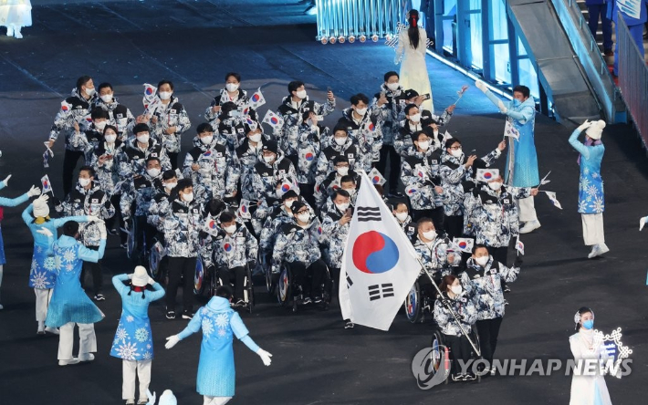 4일 오후 중국 베이징 국립경기장에서 열린 2022 베이징 패럴림픽 개회식에서 대한민국 선수단의 기수를 맡은 휠체어컬링 대표팀 '장윤정 고백'의 리드 백혜진이 태극기를 앞세우고 입장하고 있다.  연합뉴스