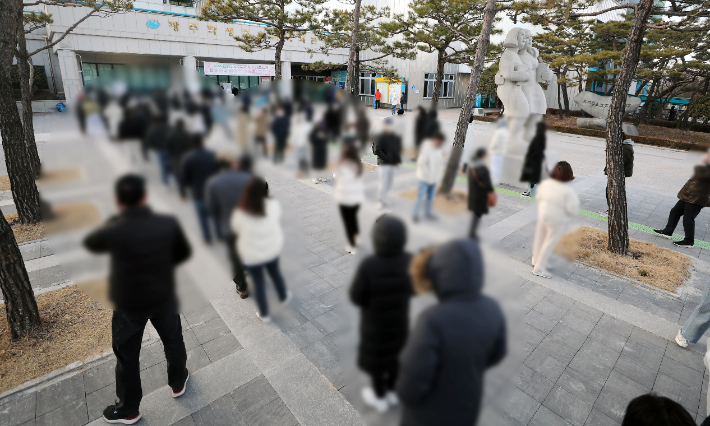 지난 5일 오후 광주 서구 학생교육문화회관에 마련된 상무1동 사전투표소에서 확진·격리자들이 사전투표를 하기 위해 줄 서 있는 모습. 연합뉴스