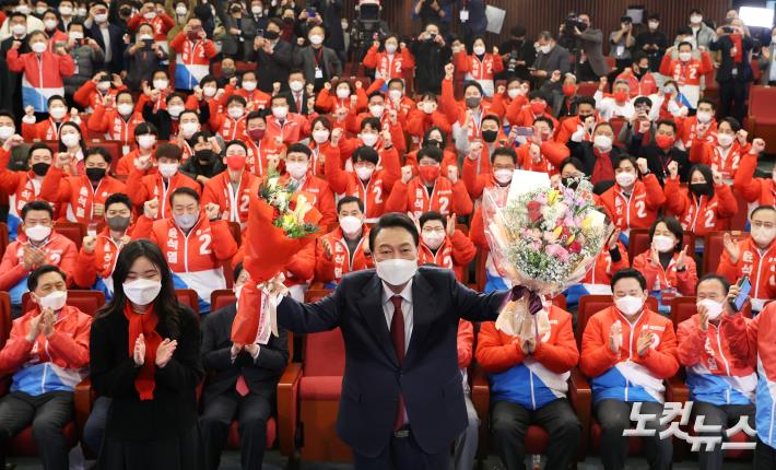 윤석열 국민의힘 대선 후보가 10일 새벽 서울 여의도 국회 도서관에 마련된 개표상황실을 찾아 당선 축하 꽃다발을 받고 있다.