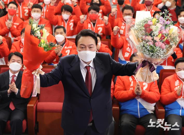 윤석열 국민의힘 대선 후보가 10일 새벽 서울 여의도 국회 도서관에 마련된 개표상황실을 찾아 당선 축하 꽃다발을 받아 들고 있다.