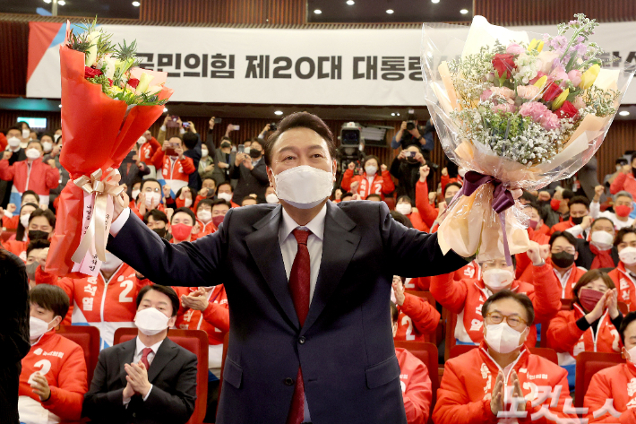 윤석열 대통령 당선인이 10일 새벽 서울 여의도 국회도서관에 마련된 '국민의힘 제 20대 대통령선거 개표상황실'을 찾아 꽃다발을 받은 뒤, 취재진을 향해 포즈를 취하고 있다. 윤창원 기자