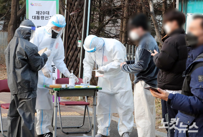 제20대 대통령 선거 본투표일인 9일 오후 서울 강남구 언주중학교에 마련된 삼성2동 제3투표소에서 코로나19 확진 유권자들이 투표 전 본인확인을 하고 있다. 황진환 기자