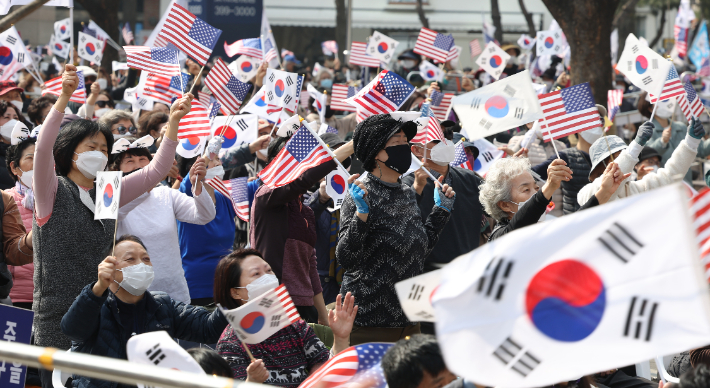 코로나19 신규 확진이 팬데믹 이후 최다를 기록한 12일 오후 서울 중구 감리교 회관 앞에서 전광훈 사랑제일교회 담임 목사가 대표로 있는 국민혁명당 주최로 열린 1천만 자유 통일 기도회에서 참석자들이 태극기와 성조기를 흔들며 찬송을 부르고 있다. 연합뉴스