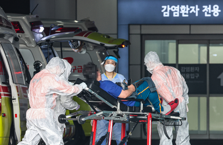 서울 중랑구 서울의료원에서 119 구급대원과 의료진이 병원에 도착한 환자를 감염병 전문 병동으로 이송하고 있다. 연합뉴스