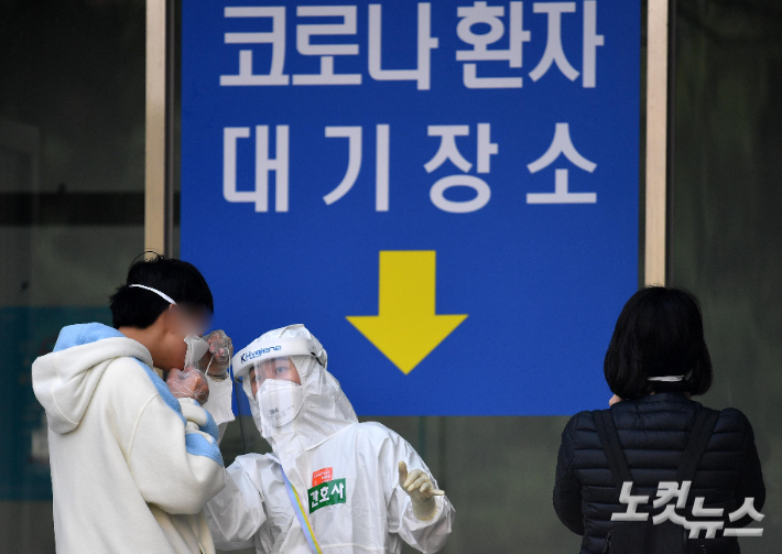 의료진이 코로나19 환자에게 마스크를 교체 착용시키고 있다. 박종민 기자