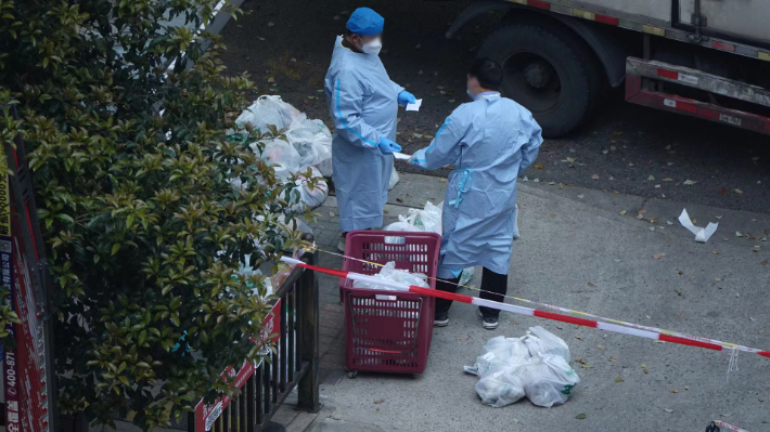 중국 상하이 창닝구의 한 아파트 단지 입구에서 방역복을 입은 봉사자들이 단지 정문 앞까지 배달된 식료품을 주문한 가정에 가져다주고 있다. 연합뉴스