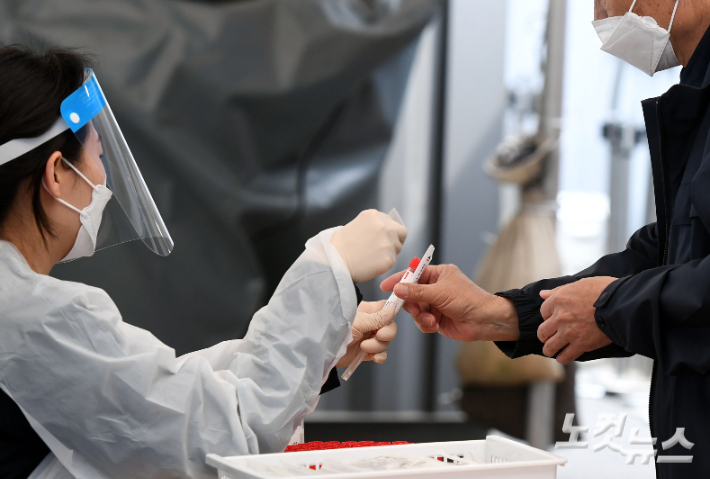 지난 18일 서울역광장에 마련된 선별진료소에서 의료진이 코로나19 PCR 진단키트를 한 시민에게 건네고 있다. 황진환 기자