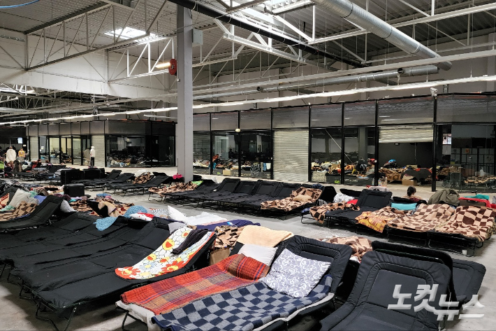 간이침대들로 가득 찬 폴란드 바르샤바에의 한 난민 캠프. 거대한 국제 박람회장 공간 전체를 임시 숙소로 사용하고 있다. 정착지를 찾지 못해 이곳에서 두 달 넘게 생활하는 이들도 있다.    